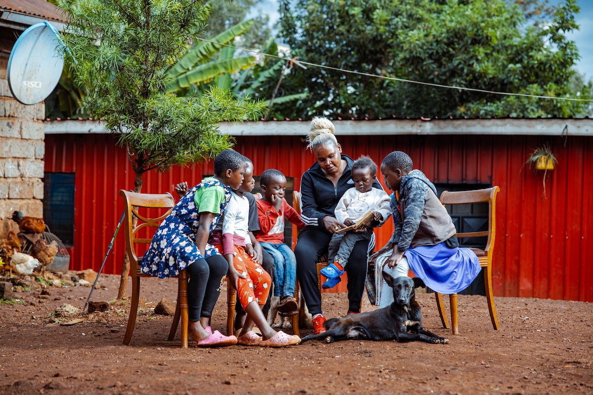 An adult reading with children outside their home