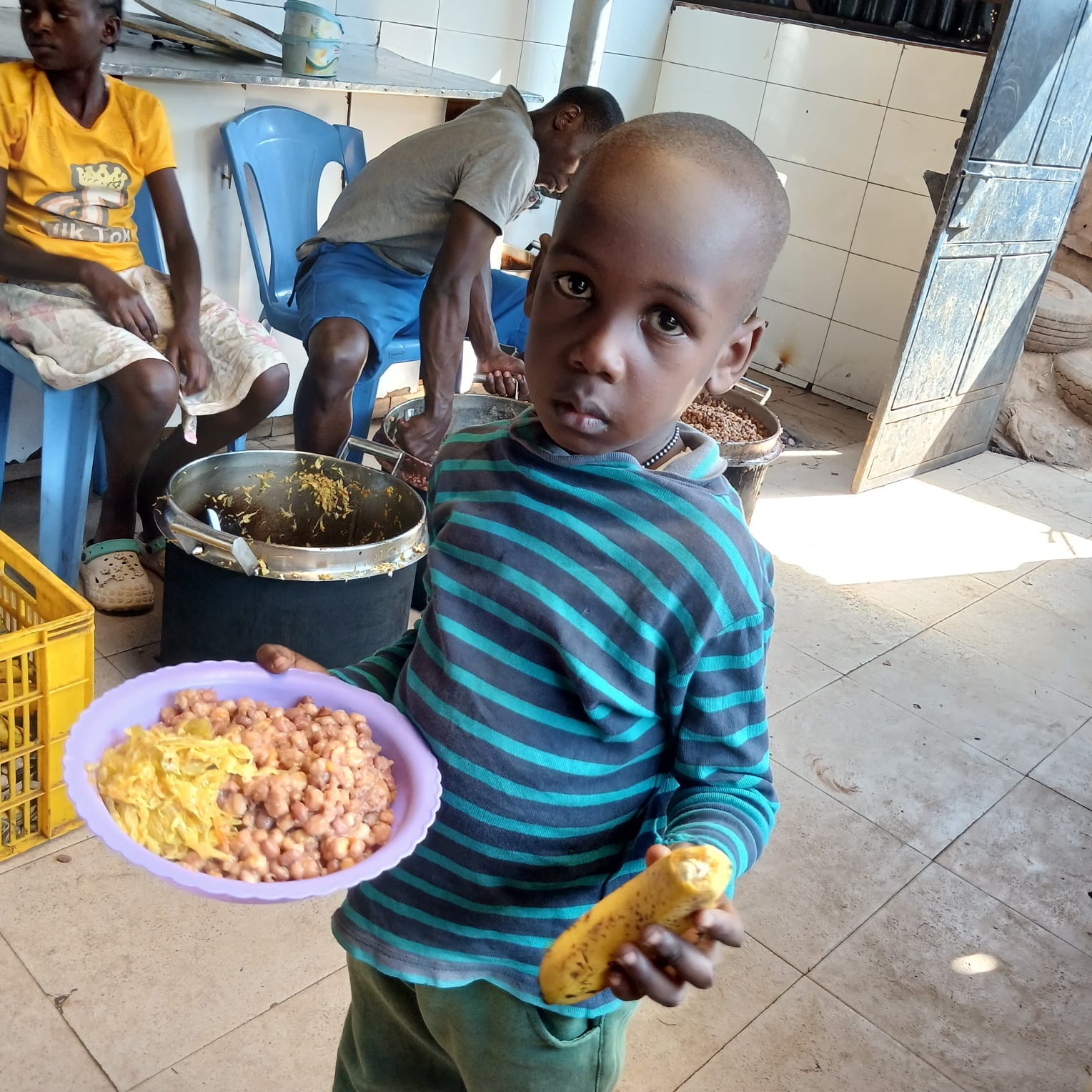 A child carrying beans, vegetables and a banana