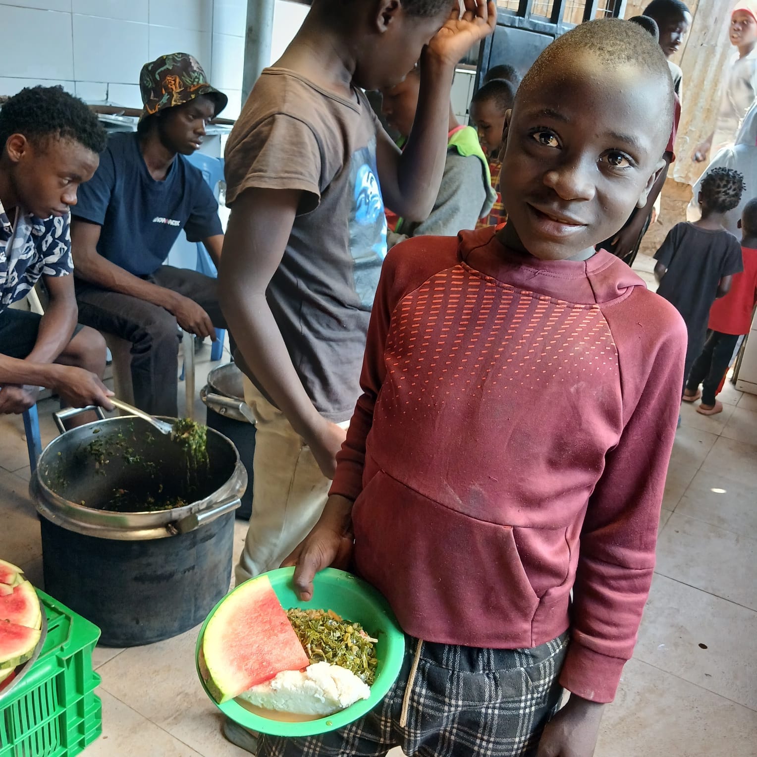 A child smiling with a meal in the community kitchen